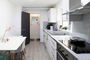 Une cuisine moderne avec des meubles blancs, une cuisinière noire et une fenêtre donnant sur la rue.