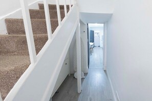 Un escalier menant à un palier d’où l’on peut voir une pièce avec une porte blanche et une petite table.
