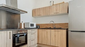 A modern kitchen with wooden cabinets, a stainless steel range hood, a microwave, an oven, and a refrigerator. - Beautiful sea view apartment, hyper center Ajaccio (Ajaccio)