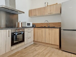 A modern kitchen with wooden cabinets, a stainless steel range hood, a microwave, an oven, and a refrigerator. - Beautiful sea view apartment, hyper center Ajaccio (Ajaccio)