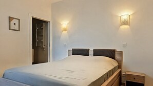 A bedroom with a wooden bed, two wall-mounted lights, a nightstand, and a door. - Beautiful sea view apartment, hyper center Ajaccio (Ajaccio)