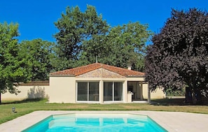 A house with a swimming pool, large windows, and a tiled roof.