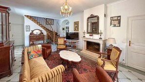 A traditional living room with a sofa, armchairs, a television, a fireplace, and a staircase. - Gorgeous home in Tauriac (Tauriac)