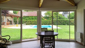 A covered patio with a table and chairs, large sliding glass doors, a pool, and a well-maintained lawn. - Gorgeous home in Tauriac (Tauriac)