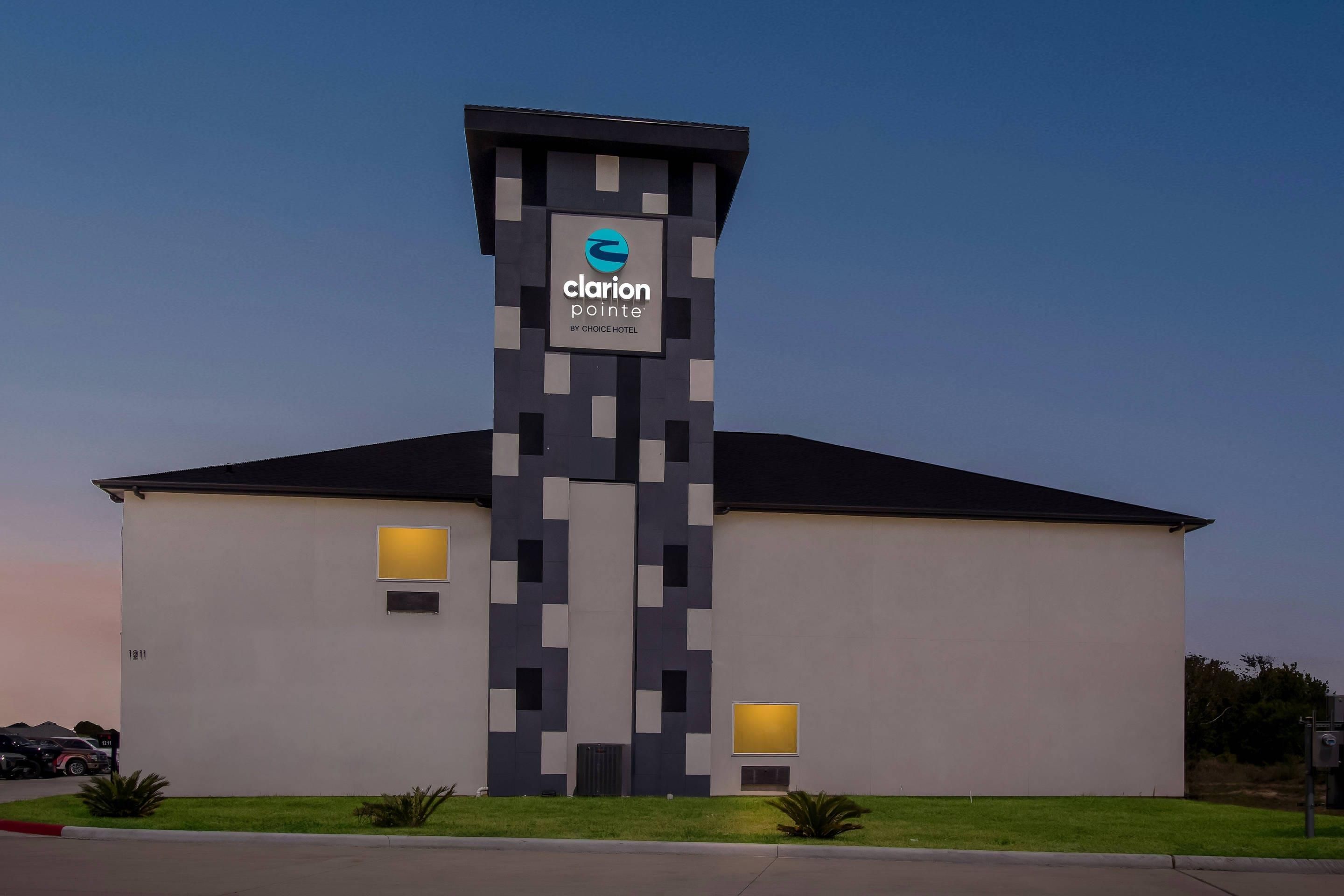 A modern hotel with a distinctive tower featuring a logo and the name 'Clarion Pointe' by Choice Hotel.