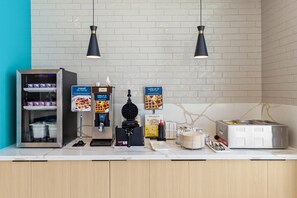A self-service food station with yogurt, waffles, and a waffle maker.