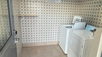 Pesutila, jossa on kyltti, josta ilmenee, että se on tarkoitettu vieraille, sekä pesukone ja kuivausrumpu.