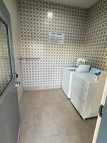 Zona de lavandería con letrero para huéspedes, lavadora y secadora.