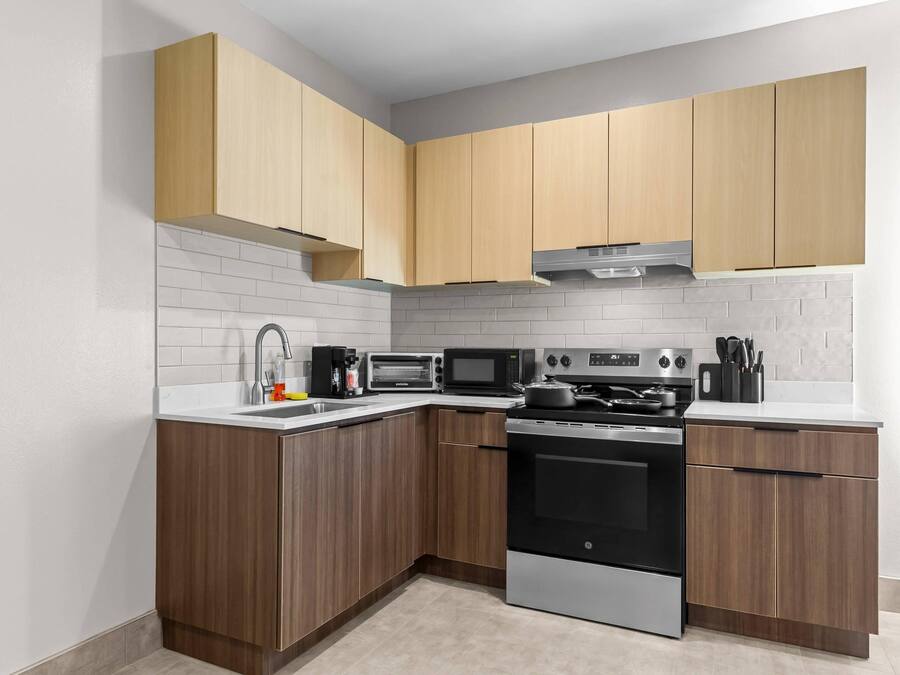 A modern kitchen with wooden cabinets, a stainless steel oven, and a microwave.