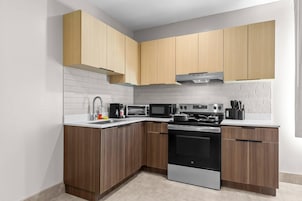 Una cocina moderna con armarios de madera, horno de acero inoxidable y microondas.