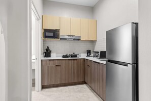 Una cocina compacta con armarios de madera, un refrigerador de acero inoxidable, un microondas y un tostador.