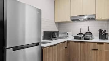 Una cocina moderna con un refrigerador de acero inoxidable, un microondas integrado, un horno tostador y una estufa con ollas y sartenes.