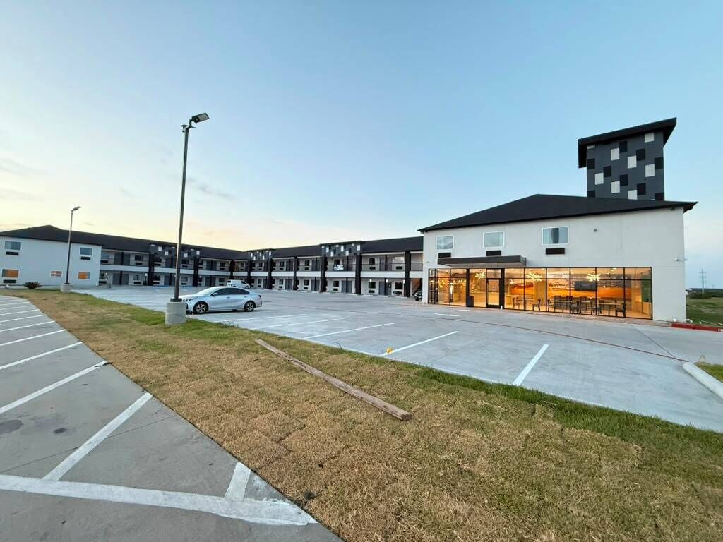 A modern building with a parking lot, a car, and a grassy area.