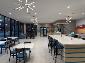 Um restaurante moderno com área de bar, mesas e vista para a rua.