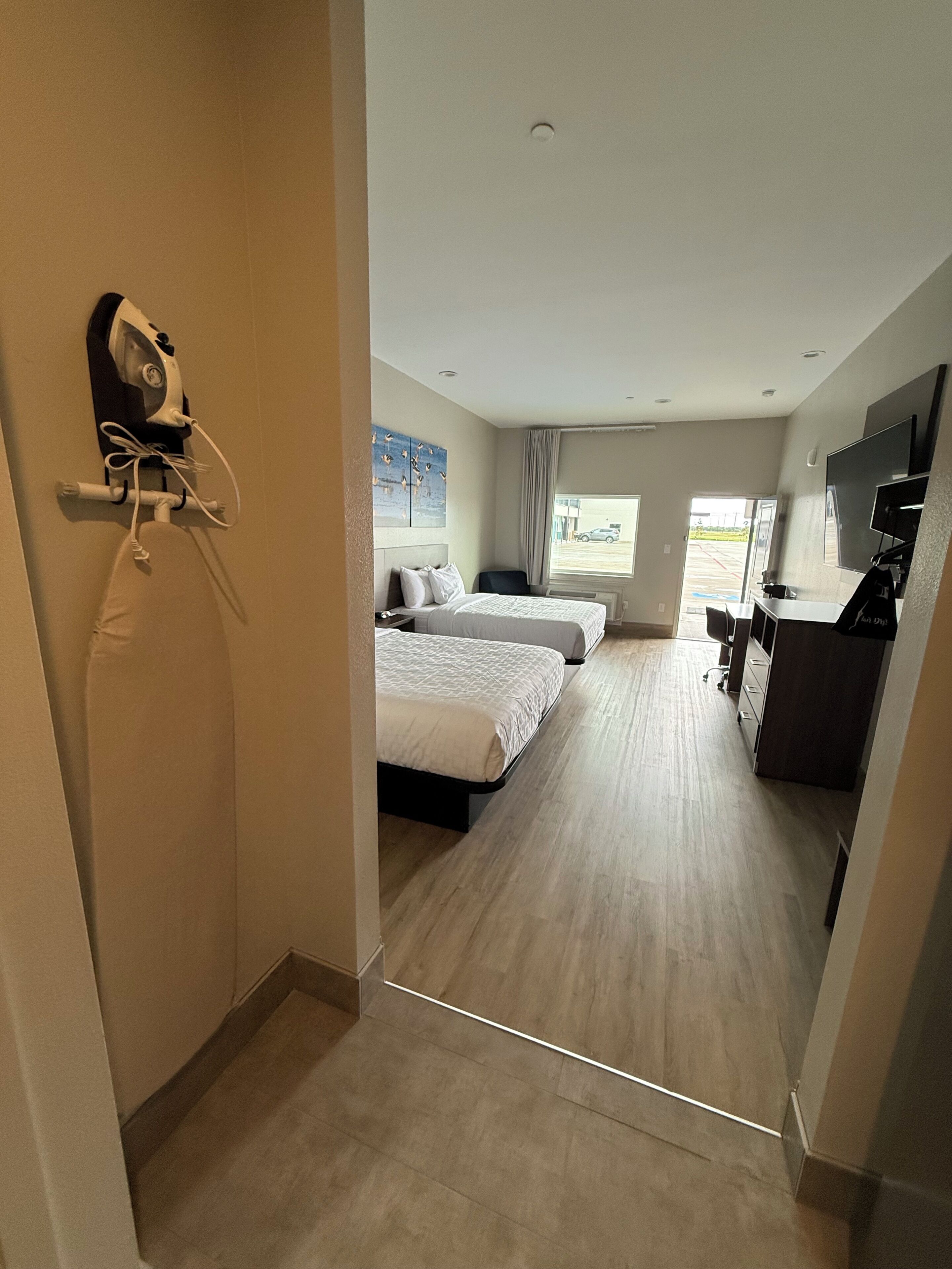 A hotel room with a bed, a desk, a chair, and a television.