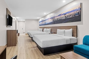Habitación de hotel con una cama grande, un escritorio, una silla y un televisor montado en la pared.