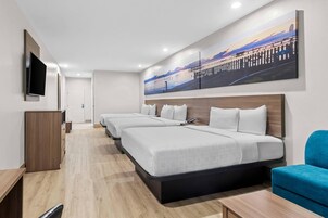 A hotel room with a large bed, a desk, a chair, and a TV mounted on the wall.