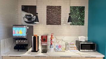 Een kitchenette met een koffiezetapparaat, een magnetron en een Nespresso-apparaat.