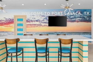 A bar area with a view of the ocean and a sunset, featuring a welcome sign for Port Lavaca, TX.