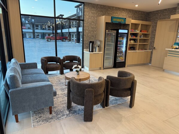 A modern interior with seating, a refrigerator, and a view of the outside. - Clarion Pointe Port Lavaca (Port Lavaca)