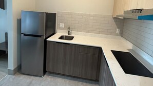 A modern kitchen with a stainless steel refrigerator, a sink, and wooden cabinets. - Clarion Pointe Port Lavaca (Port Lavaca)