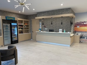 Zona de recepción con mostrador, estación de hidratación y área de estar.