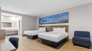 Quarto de hotel com duas camas, uma escrivaninha, uma cadeira e uma pintura grande na parede.