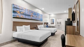 Habitación de hotel con dos camas, un escritorio, un televisor y un cuadro grande en la pared.