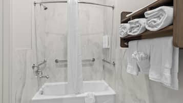 Eine Dusche mit Glastür, einer Handbrause und einem Handtuchhalter mit gefalteten Handtüchern.