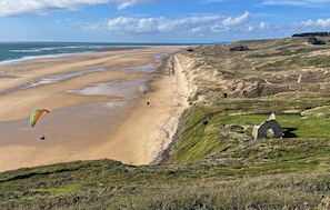 A beach with a dune buggy path, a kite surfer, and a stone ruin. - Beautiful home in Barneville Carteret with WiFi (Barneville Carteret)