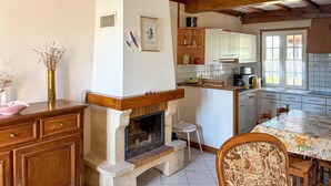 Een keuken met een open haard, houten kastjes, een eettafel en een keukeneiland.