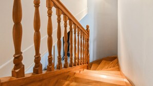 Eine Holztreppe mit Handlauf und einer Lampe darüber.