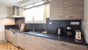 Eine moderne Küche mit Gasherd, Spüle und Kaffeemaschine.
