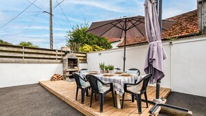 Eine Terrasse mit Holzdeck, einem Tisch für vier Personen und einem Pizzaofen.