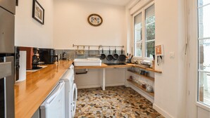 Een moderne keuken met een houten aanrecht, een ingebouwde wasmachine, een betegelde spatwand en een raam met uitzicht.