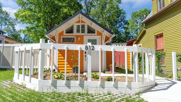 Une maison avec une clôture blanche, au numéro 812, entourée de verdure et sous un ciel dégagé.