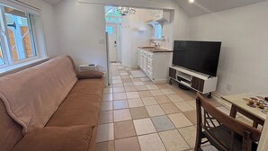 Un espace de vie compact comprenant un canapé, un téléviseur, une table à manger et un coin cuisine.