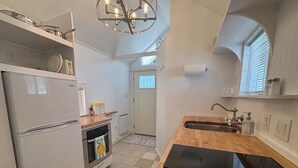 Une cuisine compacte équipée d’un réfrigérateur, d’un four et d’un plan de travail en bois.