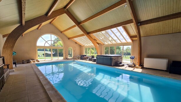 An indoor swimming pool with a high ceiling, arched windows, and a view of the outdoors. - Beautiful home in Aveze with house a panoramic view (Aveze)
