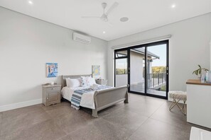 A modern bedroom with a bed, nightstand, and a view of the outdoors through a sliding door. - Room-yellow-tail Room - Staynest Guestho (Ballito)