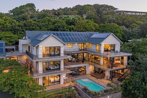 A modern multi-story house with solar panels, a swimming pool, and a lush surrounding. - Room-yellow-tail Room - Staynest Guestho (Ballito)