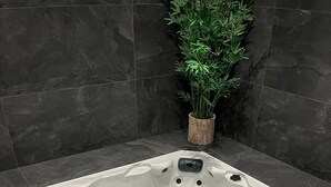 A hot tub with multiple jets, a control panel, and a small plant in the corner.