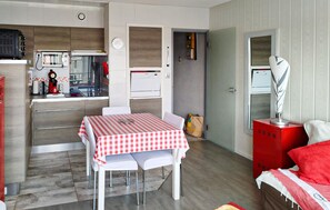 A compact living space with a kitchenette, a dining area with a checkered table, and a red cabinet. - Bel app. en première ligne (Biscarrosse)