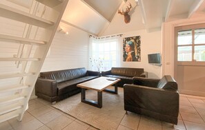 Ein Wohnzimmer mit einer Sofagarnitur, einem Couchtisch, einem Fernseher und einem an der Wand befestigten Hirschkopf.