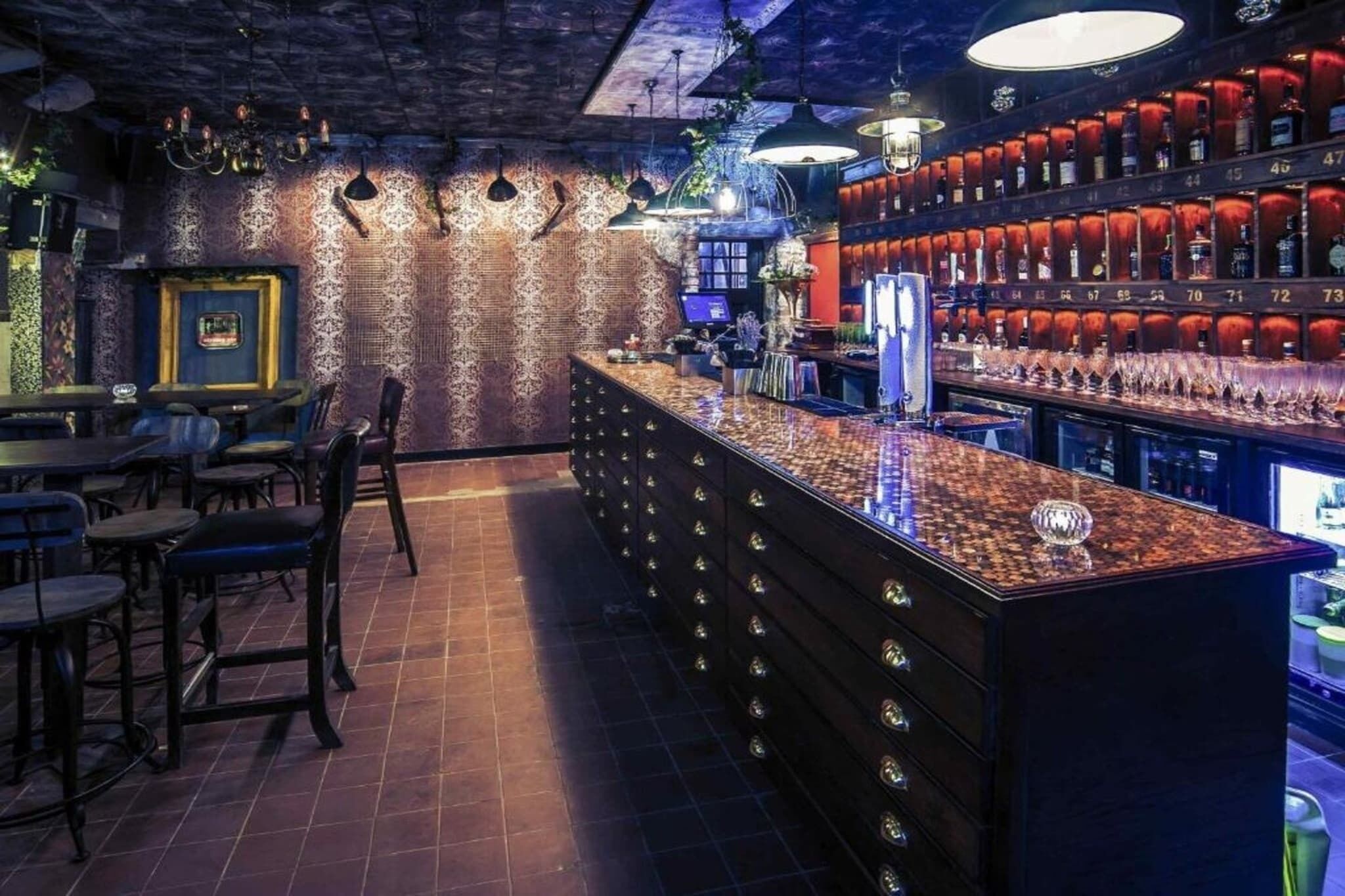 A bar area with a counter, stools, and shelves with bottles.