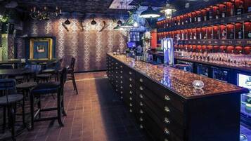 A bar area with a counter, stools, and shelves with bottles.
