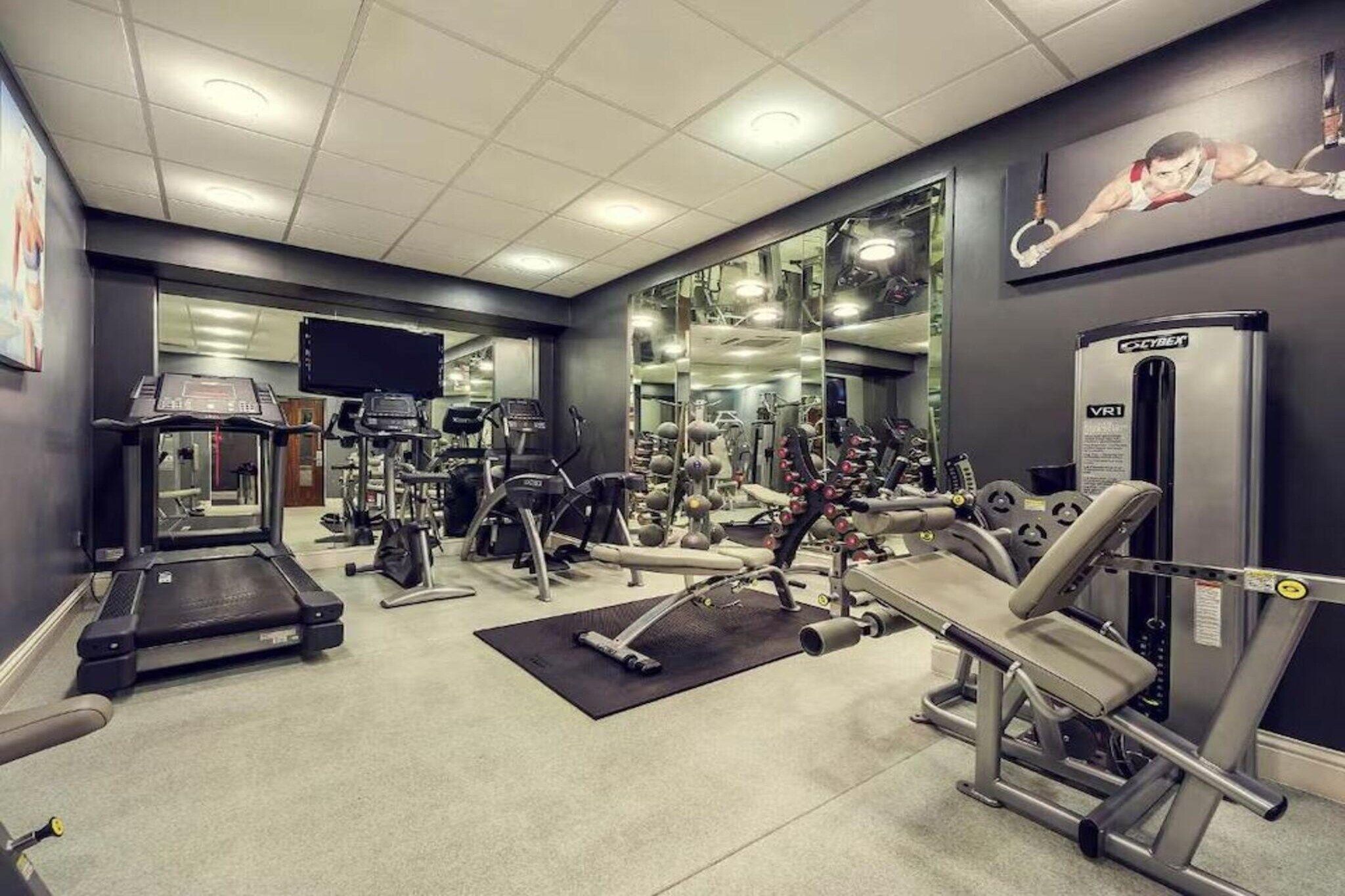 A gym with treadmills, weight machines, and a mirror wall.
