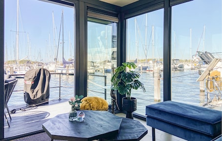 A modern room with a large window overlooking a marina, a table with a vase and a plant, and a sofa.
