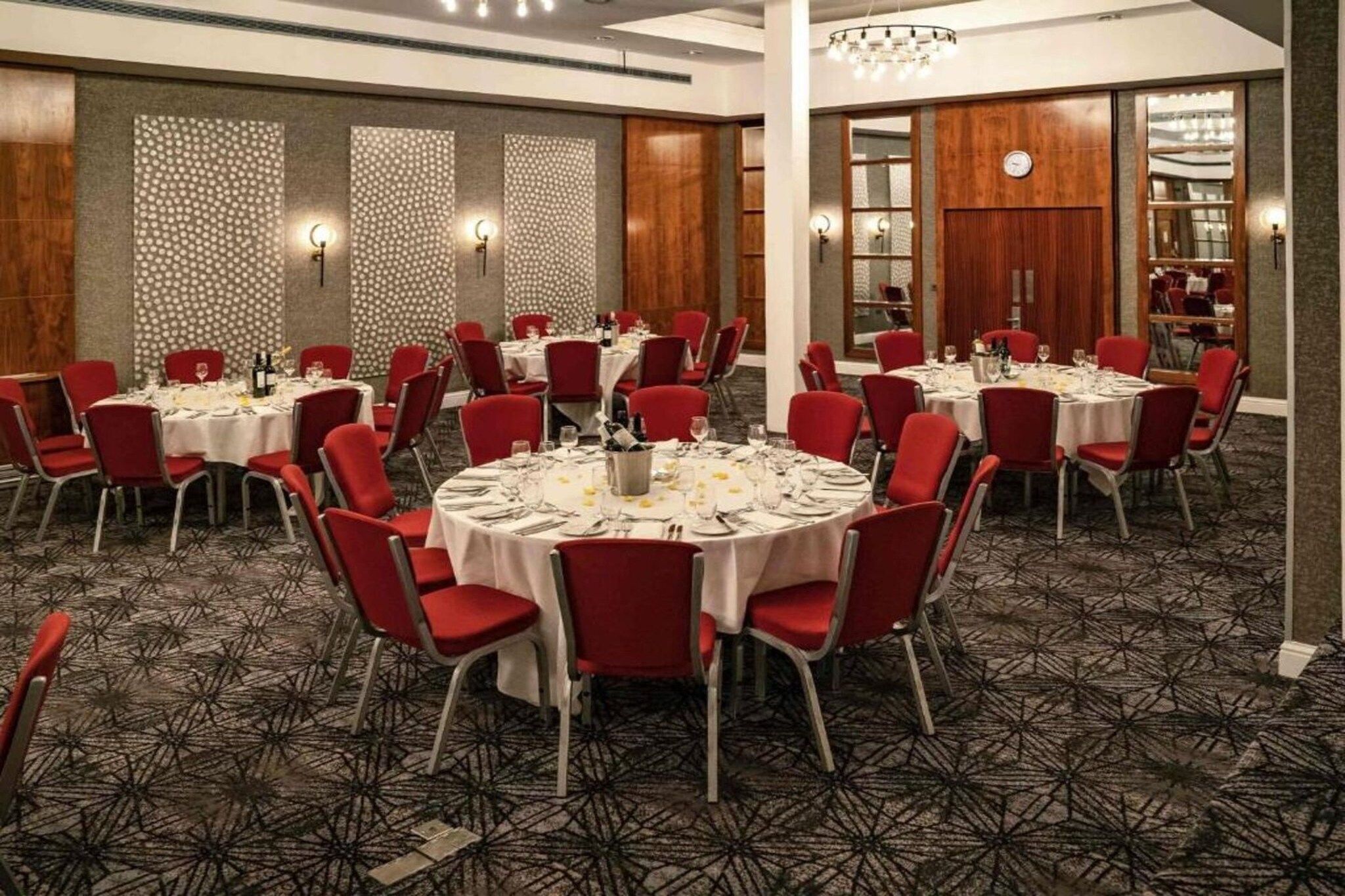 A conference room with round tables, red chairs, and a patterned carpet.