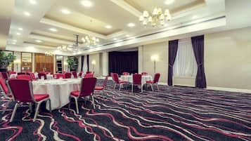 A conference room with round tables, red chairs, and a patterned carpet.